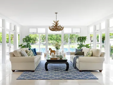A modern country living room with white and blue furnishings overlooking the pool.