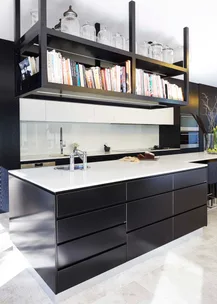 Modern kitchen with a black island, white countertop, overhead bookshelf, and glass jars.