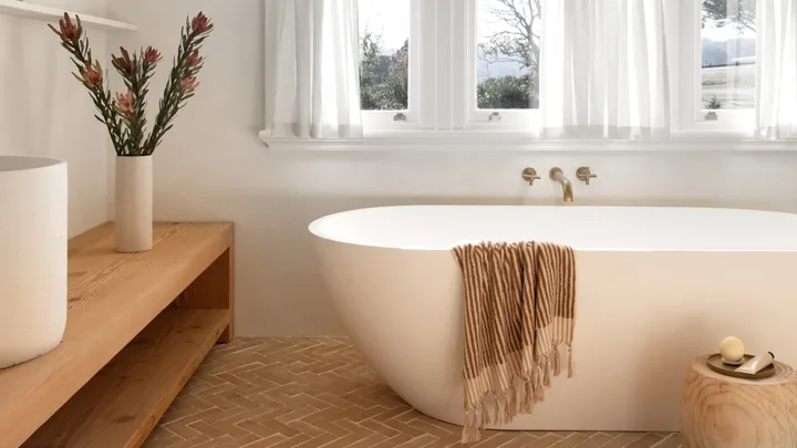A modern country bathroom in white with terracotta tiles and a freestanding tub.