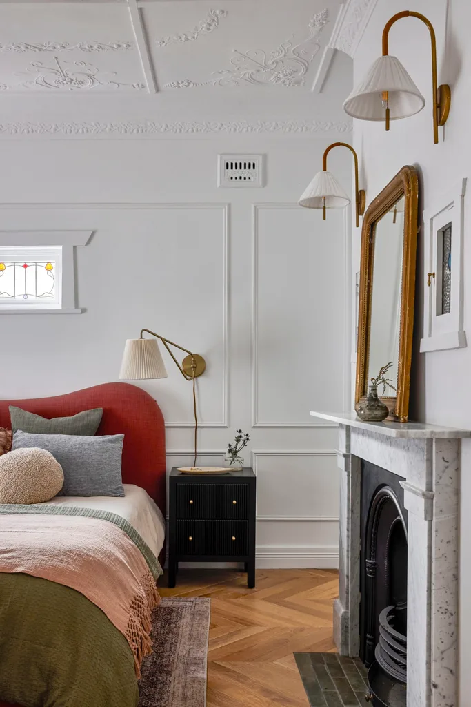 Californian-bungalow renovation main bedroom with curved bedhead, kmart linen, ceiling mouldings and marble fireplace, plus a light sconce