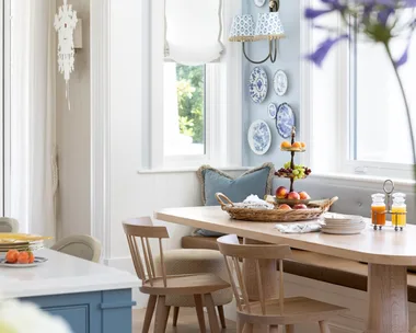 A timber breakfast nook below a wall gallery of decorative plates.