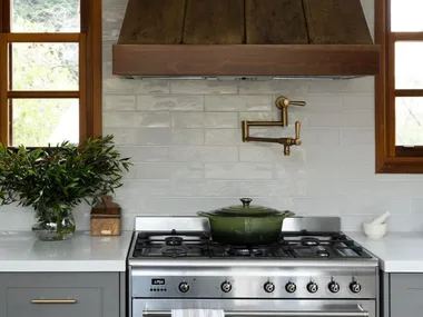 green cast iron pot on stove top with brass pot filler
