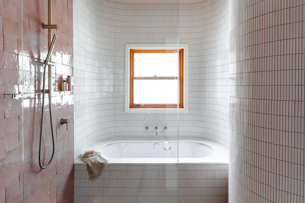 A main bathroom featuring pink zellige wall tiles, white floor tiles, white kitkat tiles and a built in bath. The tapware is brushed nickel in a curved style.