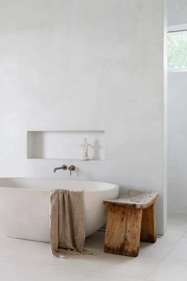 A minimalist white ensuite with a freestanding bathtub.