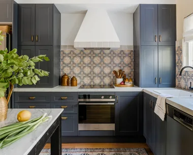 A modern kitchen with blue cabinetry, mosaic splashback tiles and marble benchtops.
