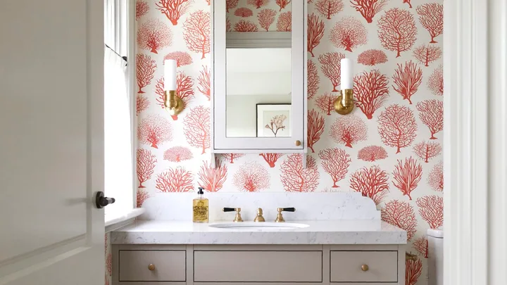 An ensuite with red tree-themed wallpaper and a marble-topped vanity.