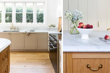 Neutral-toned kitchen with marble countertops, a bowl of peaches, and a vase of flowers on the island.