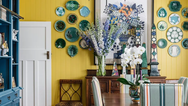 A yellow dining room with a wooden dining table and flooring and a blue cabinet.