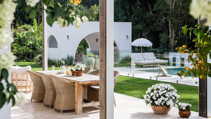 An alfresco dining area with yellow bougainvillea flowering on the pergola above it
