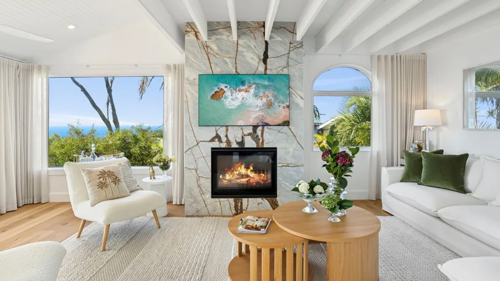 Mitch and mark from the block's newport house is for sale, featuring a white and beige living room with marble fireplace and timber coffee table 