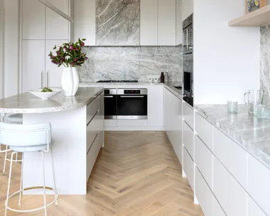 A kitchen with herringbone timber floors and grey marble details.