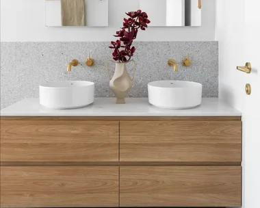 A white and grey ensuite with a timber vanity, gold tapware and arched mirrors.