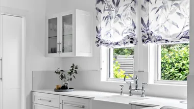 White kitchen with relaxed Roman blinds in blue and white printed linen