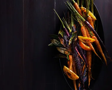 Gin and orange roasted carrots served on a table.