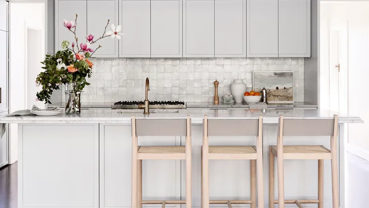 Kitchen with grey cabinetry and a vase of flowers on the island.