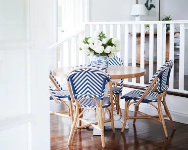 A round timber dining table set with four blue Parisian style chairs.