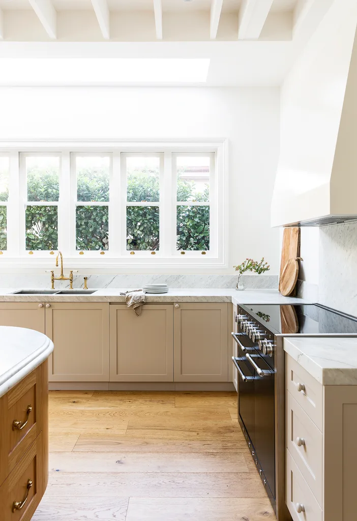 Beige and white kitchen with marble benchtops and an integrated dishwasher.